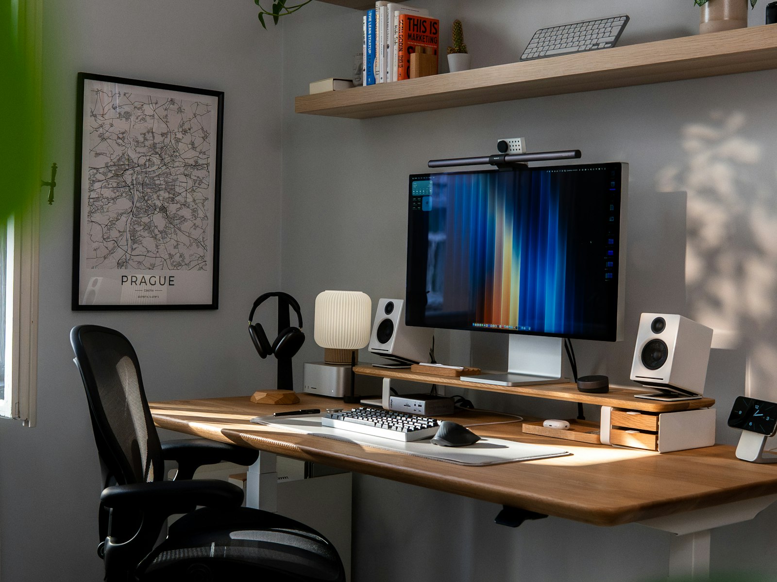 A tidy home office desk with a monitor, lamp and plants